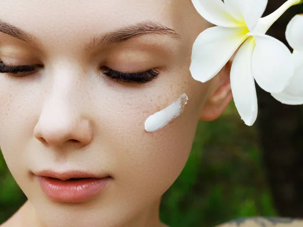 Glad tjej med fräknar. Begreppet en frisk hud. Porträtt av en vacker flicka mot en bakgrund av tropiska löv. Spa och massage koncept. Naturlig skönhet — Stockfoto