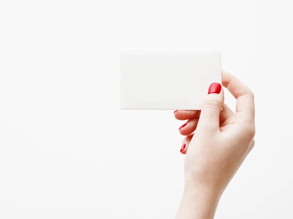 Flat lay, top view. Beauty and fashion concept. Beautiful female hands with red manicure. Minimal style. Minimalist photography. Pale composition with girl's hand holding card on white background — Stock Photo, Image