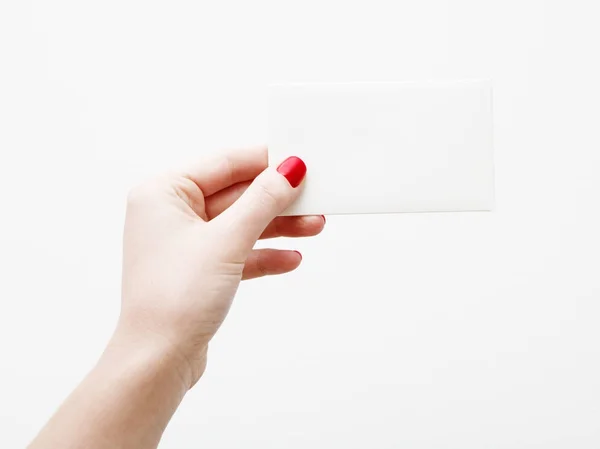 Flat lay, top view. Beauty and fashion concept. Beautiful female hands with red manicure. Minimal style. Minimalist photography. Pale composition with girl's hand holding card on white background — Stock Photo, Image