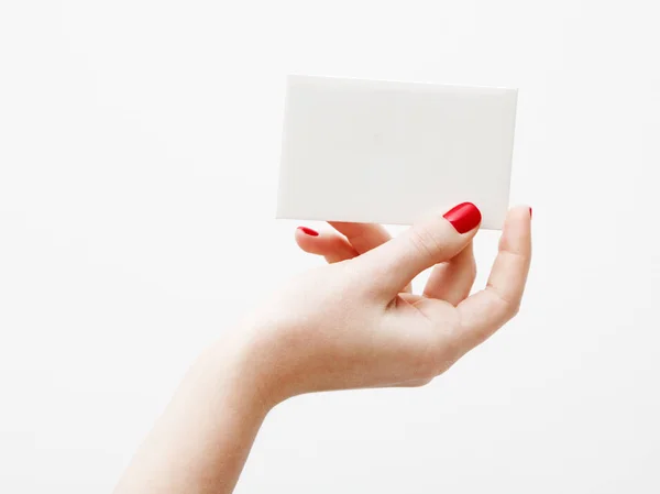 Deitado plano, vista superior. Conceito de beleza e moda. Belas mãos femininas com manicure vermelho. Estilo mínimo. Fotografia minimalista. Composição pálida com cartão de mão da menina no fundo branco — Fotografia de Stock