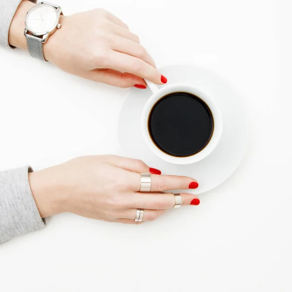 Acostado. Vista superior. Estilo mínimo. Moda minimalista y fotografía de belleza. De buen humor. Una chica en una manicura suéter sostiene una taza de café blanco sobre un fondo de mesa blanco. Relojes y joyas — Foto de Stock