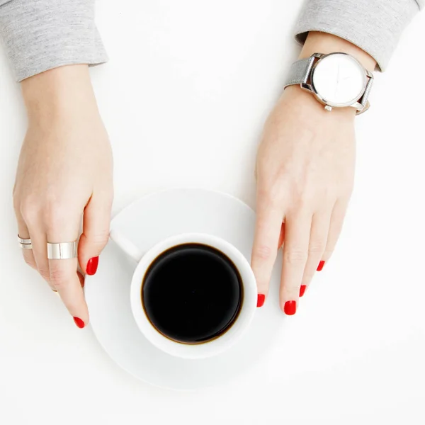 Acostado. Vista superior. Estilo mínimo. Moda minimalista y fotografía de belleza. De buen humor. Una chica en una manicura suéter sostiene una taza de café blanco sobre un fondo de mesa blanco. Relojes y joyas — Foto de Stock