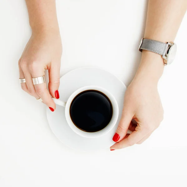 Acostado. Vista superior. Estilo mínimo. Moda minimalista y fotografía de belleza. De buen humor. Una chica en una manicura suéter sostiene una taza de café blanco sobre un fondo de mesa blanco. Relojes y joyas — Foto de Stock