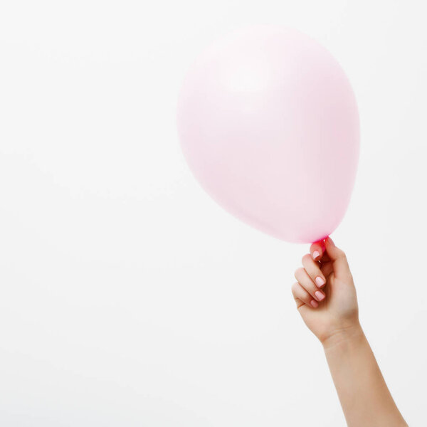 Minimalist fashion and beauty photo. Hand holding a pink balloon on a white wall background with shadow reflection. The concept of St. Valentine's Day or birthday. The 14th of February