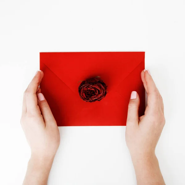 Moda minimalista e foto de beleza. Uma carta de amor num envelope vermelho com uma rosa. As mãos femininas põem uma carta de amor. O conceito de Dia de São Valentim. Fotografia romântica. 14 de Fevereiro — Fotografia de Stock