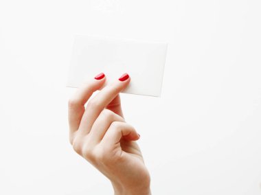 Düz yatıyordu, en iyi görünüm. Güzellik ve moda kavramı. Güzel eller kırmızı manikür ile. En az tarzı. Minimalist fotoğraf. Beyaz arka plan üzerinde kart tutan kız el ile soluk kompozisyon