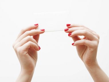 Düz yatıyordu, en iyi görünüm. Güzellik ve moda kavramı. Güzel eller kırmızı manikür ile. En az tarzı. Minimalist fotoğraf. Beyaz arka plan üzerinde kart tutan kız el ile soluk kompozisyon