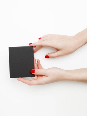 Düz yatıyordu, en iyi görünüm. Güzellik ve moda kavramı. Güzel eller kırmızı manikür ile. En az tarzı. Minimalist fotoğraf. Beyaz arka plan üzerinde kart tutan kız el ile soluk kompozisyon