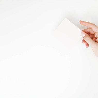 Düz yatıyordu, en iyi görünüm. Güzellik ve moda kavramı. Güzel eller kırmızı manikür ile. En az tarzı. Minimalist fotoğraf. Beyaz arka plan üzerinde kart tutan kız el ile soluk kompozisyon