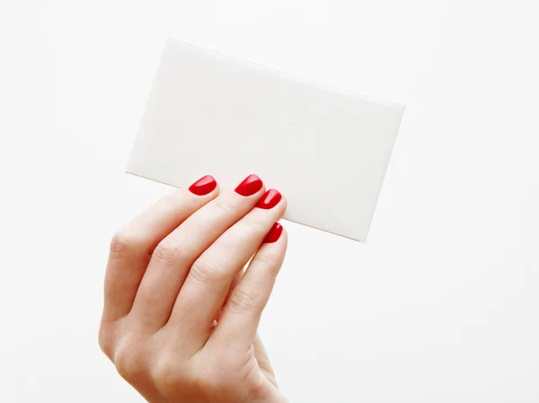 Flat lay, top view. Beauty and fashion concept. Beautiful female hands with red manicure. Minimal style. Minimalist photography. Pale composition with girl's hand holding card on white background — Stock Photo, Image