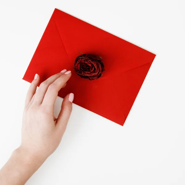 Moda minimalista e foto de beleza. Uma carta de amor num envelope vermelho com uma rosa. Mãos femininas segurando uma carta de amor. O conceito de Dia de São Valentim. Fotografia romântica. 14 de Fevereiro — Fotografia de Stock