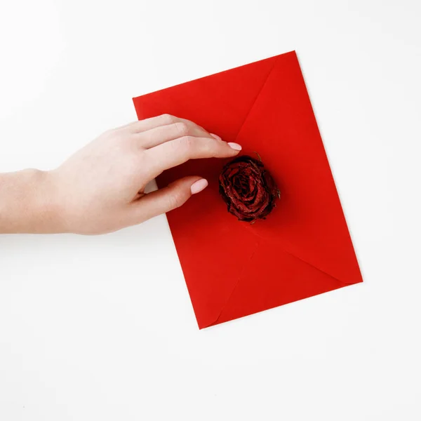 Moda minimalista e foto de beleza. Uma carta de amor num envelope vermelho com uma rosa. Mãos femininas segurando uma carta de amor. O conceito de Dia de São Valentim. Fotografia romântica. 14 de Fevereiro — Fotografia de Stock