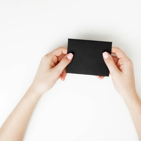 Deitado plano, vista superior. Conceito de beleza e moda. Belas mãos femininas com manicure vermelho. Estilo mínimo. Fotografia minimalista. Composição com a mão da menina segurando cartão de desconto no fundo branco — Fotografia de Stock