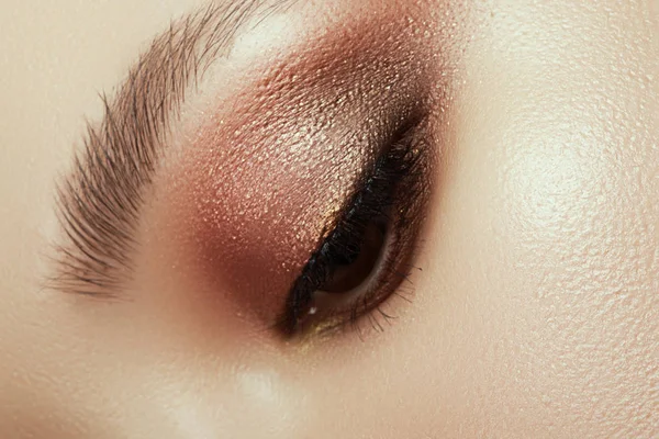 Närbild av blå kvinna ögat med vacker brun med röda och orange nyanser sotade ögon makeup. Modern mode gör upp. — Stockfoto