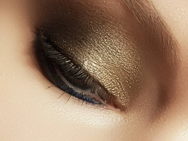 Close-up van blauw vrouw oog met prachtige gouden tinten make-up. Klassieke make-up. Make-up van de perfecte vorm en lange wimpers. Cosmetica en make-up. Close-up macro-opname van fashion ogen visage — Stockfoto