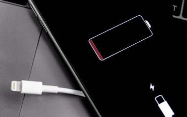 Vitrinde yıldırım kablosu ve pil logosu olan Apple iPhone akıllı telefonu. Apple, elektronik, bilgisayar yazılımı ve çevrimiçi hizmetler tasarlayan, geliştiren, satan çok uluslu bir teknoloji şirketidir. Moskova, Rusya - 12 Temmuz 2019
