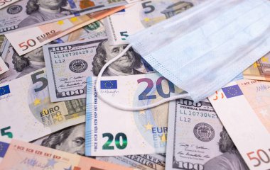 COVID-19 koronavirüs, salgın. Para dolarları, Avro banknotları ve yüz maskesi. Coronavirus küresel borsayı etkiler. Kriz ve finans kavramı.