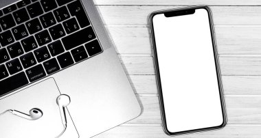 iPhone modeli ve Apple Earpod 'lu Macbook beyaz masaya yakın çekim yapıyor. Grafik görüntüleme için boş ekran cep telefonu. Moskova, Rusya - 23 Aralık 2019