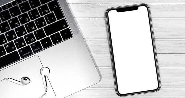 iPhone modeli ve Apple Earpod 'lu Macbook beyaz masaya yakın çekim yapıyor. Grafik görüntüleme için boş ekran cep telefonu. Moskova, Rusya - 23 Aralık 2019
