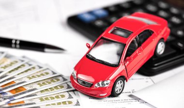 Hesap makinesi ve parası olan kırmızı araba, kağıt formuna yakın çekimde dolar.