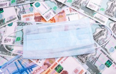 Rusya karantinayı kucaklıyor. Yüz maskeli Rus para rublesi. Coronavirus küresel borsayı etkiler. Kriz ve finans kavramı.