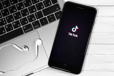Ekran iPhone 'unda TikTok logosu, defter ve kulaklıklarda Apple Earpod' lar yakın plan. TikTok video yaratmak ve paylaşmak için bir uygulamadır. Moskova, Rusya - 23 Aralık 2019