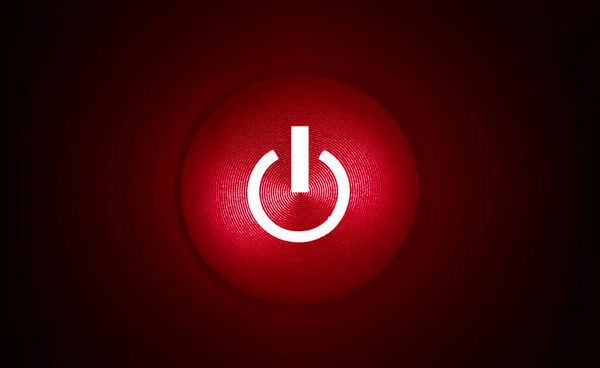red power button with red light in the dark, black background