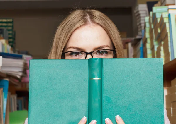 Dívka vypadá zpoza knihy brýle, Studentka — Stock fotografie