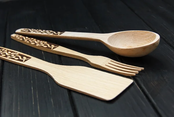 Wooden spoons utensils wood kitchen utensils lying on a black ta — Stockfoto
