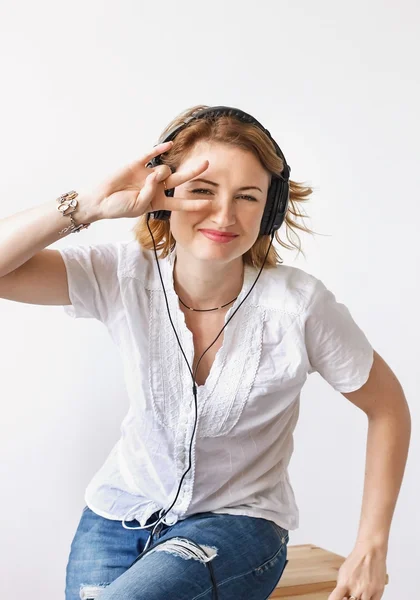 Chica con auriculares escuchando música y bailando en un s blanco — Foto de Stock