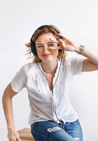 Chica con auriculares escuchando música y bailando en un s blanco — Foto de Stock