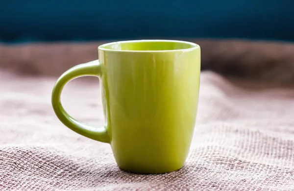 Taza verde en la mesa por la ventana en tela de saco aislado, con —  Fotos de Stock