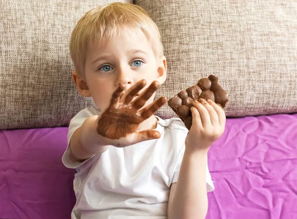 boy eating chocolate, holding a hand's candy, hands soiled in ch