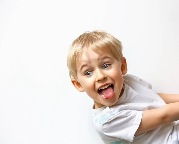 Petit garçon taquinant, montrant la langue et fait un visage, sur ba blanc — Photo