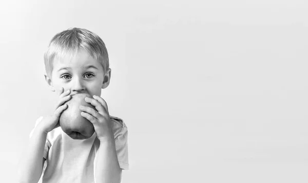 Fröhliche fröhliche Junge isst den großen Apfel, das Kind ist die Frucht gr — Stockfoto