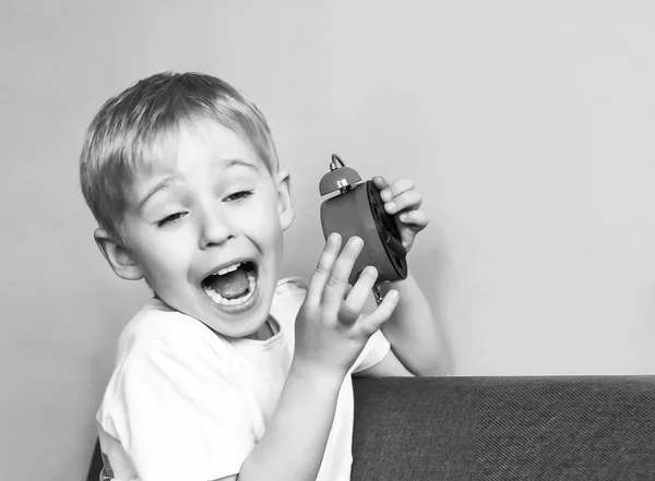 Pojken håller en väckarklocka, ett barn och tid röd, begreppet tim — Stockfoto
