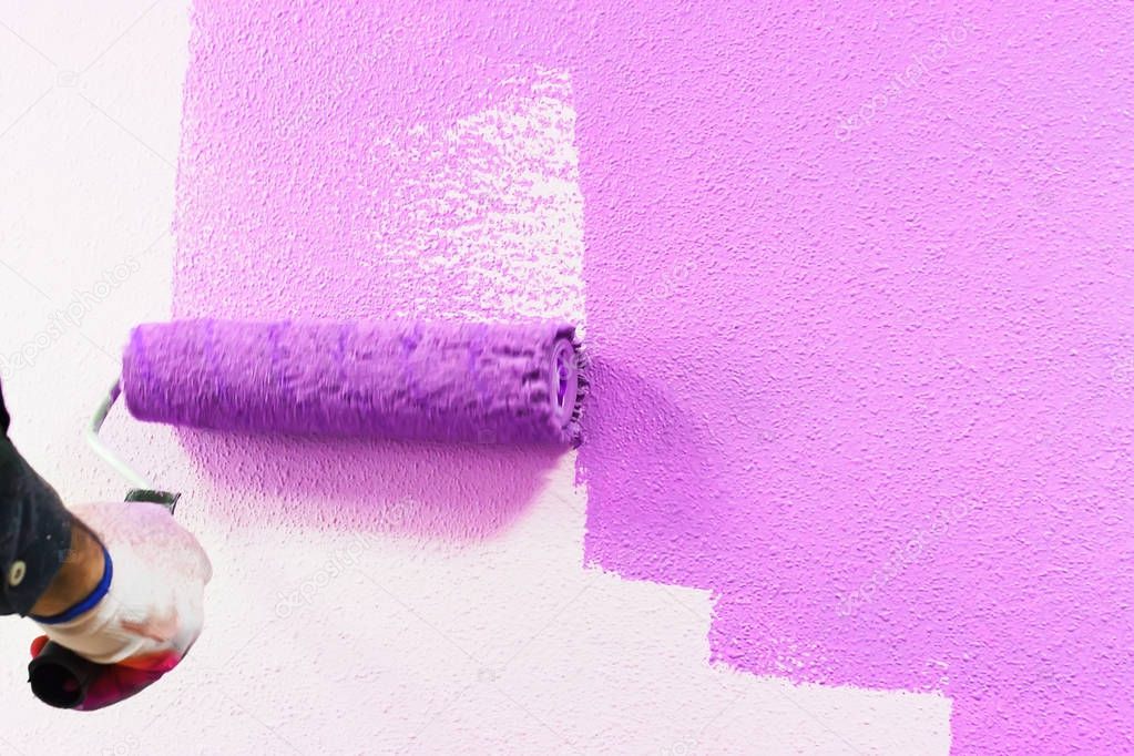 rasit hand wall paint using a paint roller while working indoors