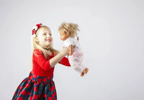Pequeña niña feliz jugando a una muñeca, en un blanco — Foto de Stock