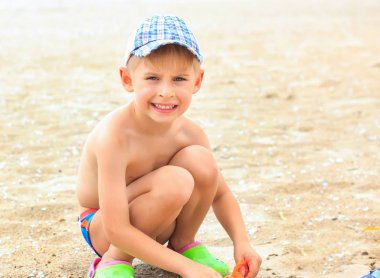 Küçük çocuk sahilde kum ile oynuyor. Yaz c bina,