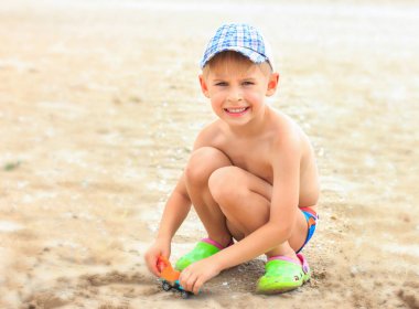 Küçük çocuk sahilde kum ile oynuyor. Yaz c bina,