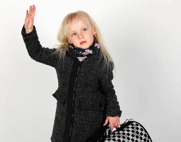 Little girl blonde in coat and with suitcase showing goodbye — Stock Photo, Image