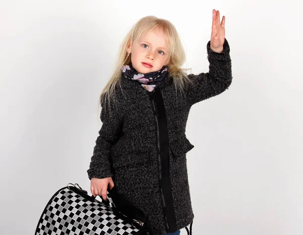 Little girl blonde in coat and with suitcase showing goodbye — Stock Photo, Image