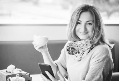 bir tablet bilgisayar ile bir fincan dinlenirken kullanan güzel kız