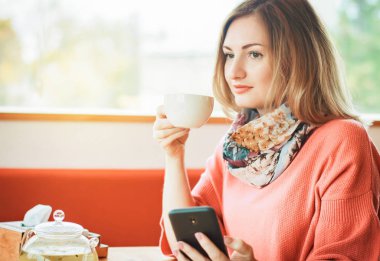düşünceli, bir kafede öğle yemeğinde, bir smartphone kullanarak güzel kız