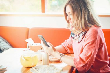 bir akıllı telefon tutarak kafede oturan güzel kız. Kahve, akıllı adamın, bir kafede bir cep telefonu kullanarak