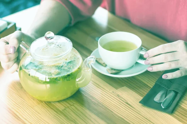 Manos de una chica en un café y beber té caliente de hierbas. fragante —  Fotos de Stock