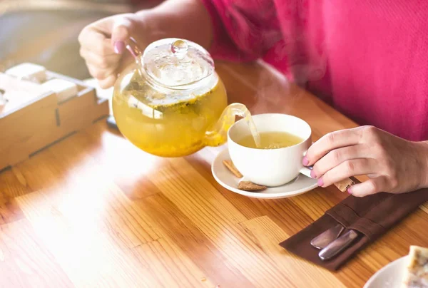 Női kezek öntsünk egy csésze forró tea. Reggeli a café.arom — Stock Fotó