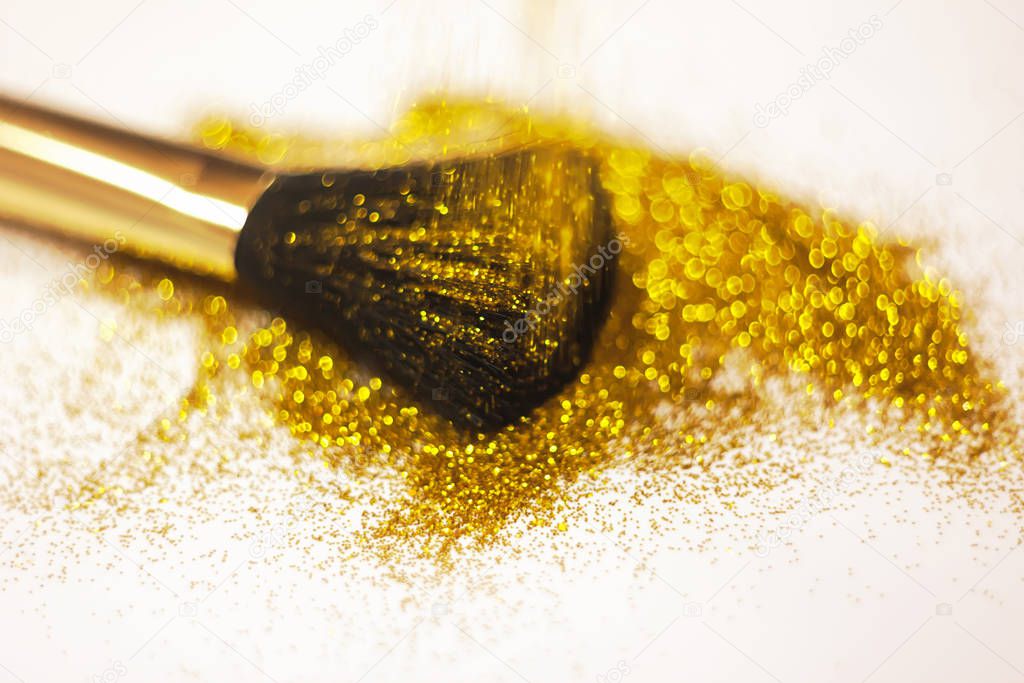 texture of gold glitter on the makeup brush and design. On white