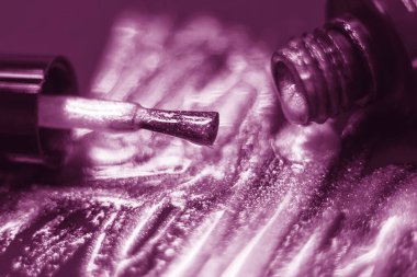 Fırçalara ve parlayan toza yakın çekim. Fırçanın ucuna çok sığ bir odak noktası. Manikürün ışıltısının dokusu. Fırçanın yanında bir şişe tırnak cilası. Kozmetik reklam konsepti