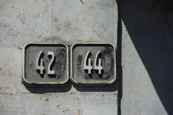 old gray wall with house numbering. numbering on the old house. Apartment number 42 and 44